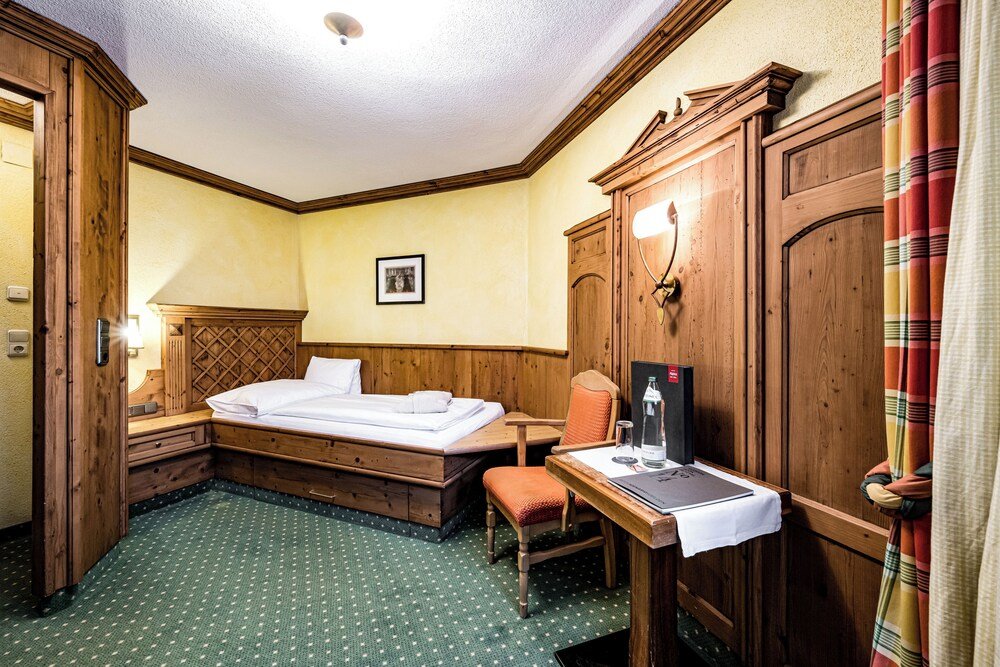 Bright hotel room with bedding and wooden details at Alpina